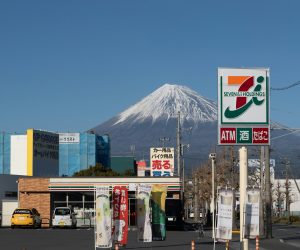 Mount Fuji visible behind a 7-Eleven store sign in Shizuoka, Japan.
